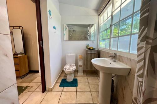 uma casa de banho com um WC, um lavatório e uma janela em Fare Tokatea - Charming Studio w Excl Beach em Iumaru