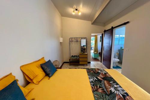 um quarto com uma cama com almofadas amarelas e um espelho em Fare Tokatea - Charming Studio w Excl Beach em Iumaru