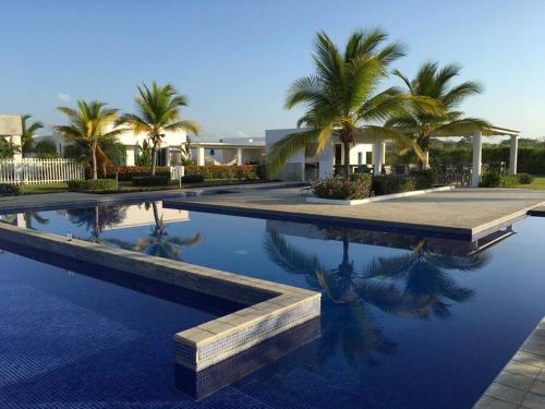 a swimming pool with palm trees and a house at Lulu Village - Beach - Pool - Pet Friendly in Coclé
