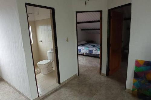 a bathroom with a toilet and a bedroom with a bed at Finca la cristalina in Moniquirá
