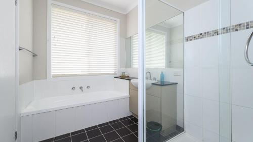 La salle de bains blanche est pourvue d'une baignoire et d'un lavabo. dans l'établissement Sandpiper 9 - Close to Town and Beach, à Inverloch