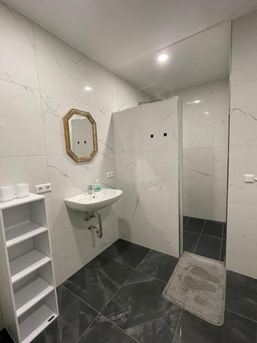 La salle de bains blanche est pourvue d'un lavabo et d'une douche. dans l'établissement Pension Hammer, à Mensfelden