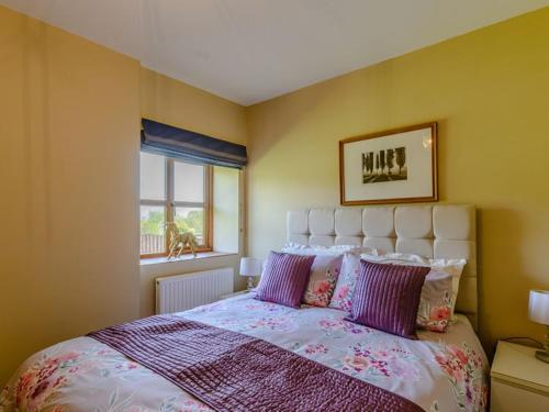 a bedroom with a large bed with purple pillows at Stone Cottage in Shrewsbury