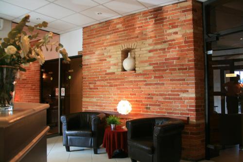 a brick wall with two chairs and a table at Hotel de Bordeaux in Toulouse