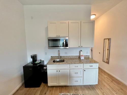 a kitchen with white cabinets and a sink at Unit 7 Maui Ohana Modern Studio in Wailuku