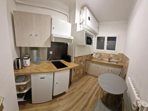 une petite cuisine avec des armoires blanches et une table dans l'établissement Studio confortable 10 min du Palais des festivals, à Cannes