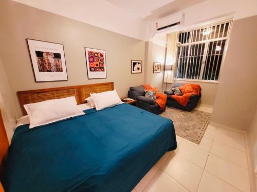 1 dormitorio con 1 cama azul y 2 sillas en Estúdio completo entre Copacabana e Ipanema em frente ao metro a 300 metros da praia, en Río de Janeiro