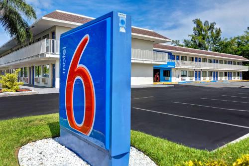 a blue gas pump sign in front of a parking lot at Motel 6 Dania Beach in Dania Beach