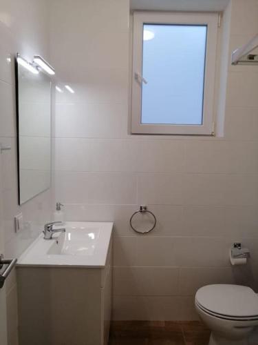 a bathroom with a sink and a toilet and a window at Casa da Praia da Poça - Apartamento Íris in Estoril