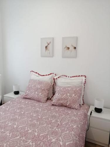 a bedroom with a pink bed with three pictures on the wall at Casa da Praia da Poça - Apartamento Íris in Estoril