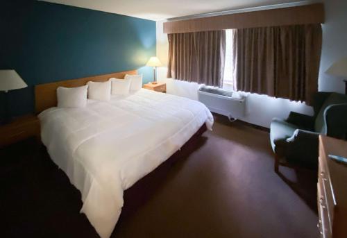 um quarto de hotel com uma grande cama branca e uma janela em Motel 6 Norway MI em Norway