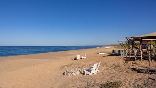a beach with chairs and a building on the sand at Villa Santa Cruz in Todos Santos