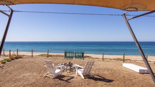 two white chairs and a table on the beach at Villa Santa Cruz in Todos Santos