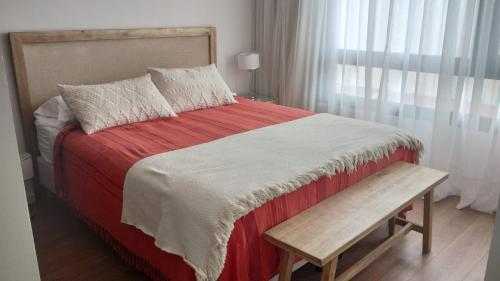 1 cama con manta roja y blanca y banco en Moderno 2 amb con Cochera en Mar del Plata