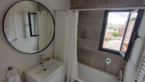 ein Badezimmer mit einem Spiegel, einem Waschbecken und einer Badewanne in der Unterkunft Moderno 2 amb con Cochera in Mar del Plata
