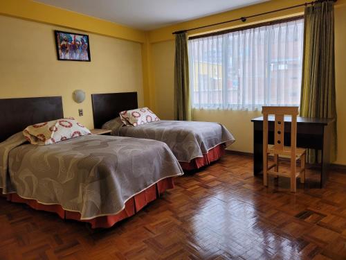 a room with two beds and a desk and a window at Hotel Nuevo Sol in La Paz