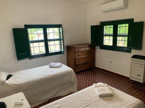 a bedroom with two beds and a dresser and windows at Las Marias in Tandil