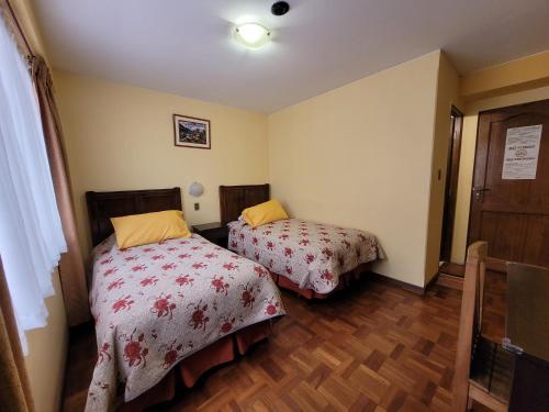 two beds in a small room with wooden floors at Hotel Nuevo Sol in La Paz