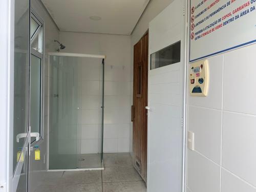 uma casa de banho com um chuveiro e uma porta de vidro em Apartamento Guarujá Lazer completo Villa Di Fiori 600mts da praia no Guarujá