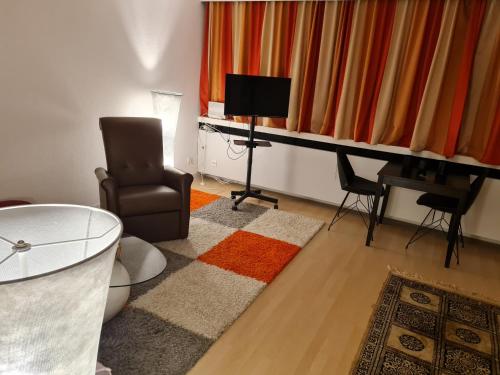 un salon avec une chaise, une table et une télévision dans l'établissement Einzimmer Apartments im Si-Centrum Stuttgart-Möhringen, à Stuttgart