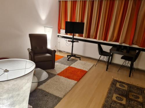 a living room with a chair a table and a television at Einzimmer Apartments im Si-Centrum Stuttgart-Möhringen in Stuttgart