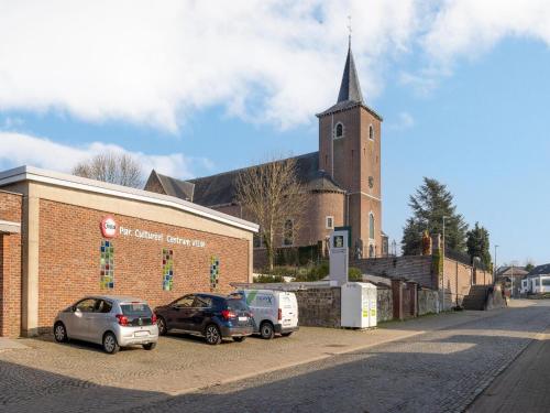 two cars parked in front of a church with a steeple at Riding School Farm Stay in Sint-Truiden