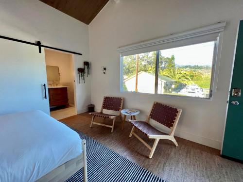 1 dormitorio con 1 cama, 2 sillas y ventana en The Presidio, en Santa Bárbara