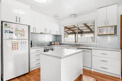 a kitchen with white cabinets and a white refrigerator at Ventnor Getaway in Ventnor