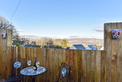 a table with two chairs and a bottle of wine on a fence at La Cantera in Merthyr Tydfil