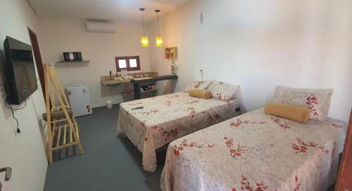 a bedroom with two beds and a desk and a television at Kbanas Milagres in São Miguel dos Milagres