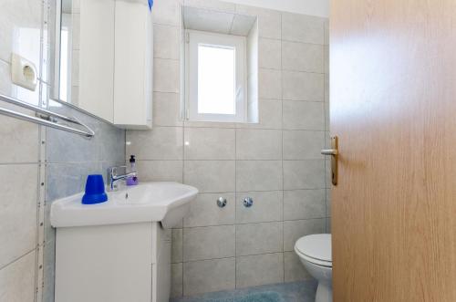 łazienka z umywalką, toaletą i oknem w obiekcie Apartments Darko by the sea w mieście Supetarska Draga