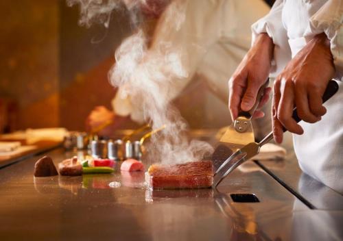 un chef cuisine de la nourriture sur un comptoir avec un couteau dans l'établissement Imperial Hotel Tokyo, à Tokyo