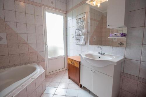 ein weißes Badezimmer mit einem Waschbecken, einer Badewanne und einem Waschbecken in der Unterkunft Apartment Sanja in Rab