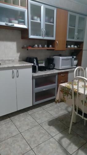 a kitchen with white cabinets and a table and a microwave at Cantinho aconchegante in Campos do Jordão