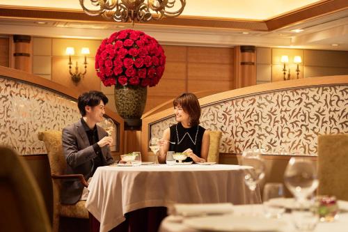 a man and woman sitting at a table in a restaurant at Imperial Hotel Tokyo in Tokyo