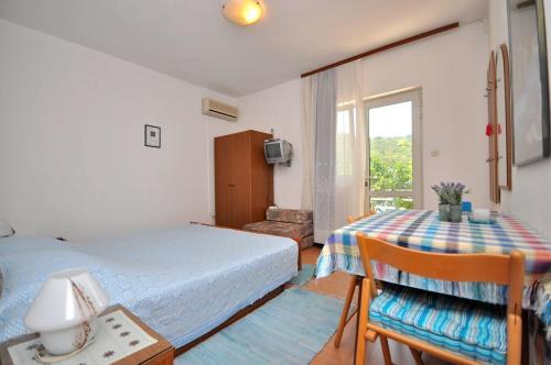 a bedroom with a bed and a table and a window at Apartments Slavica in Ubli