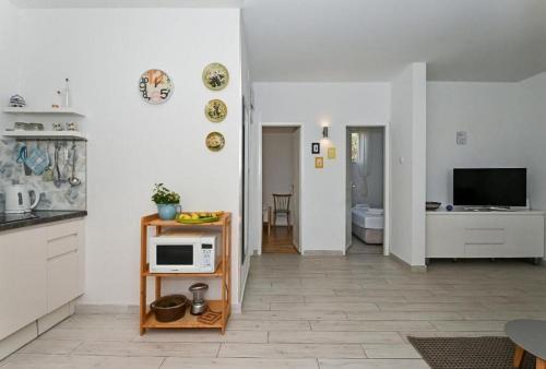 a white kitchen with a microwave on a table at Apartments Nikica in Seget Vranjica