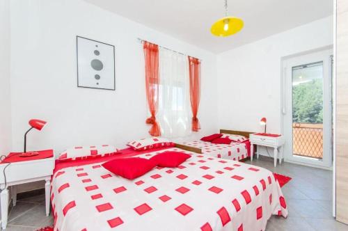 two beds in a white bedroom with red pillows at House Vatromir in Bogomolje