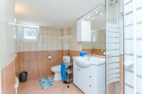 a bathroom with a white sink and a toilet at House Vatromir in Bogomolje