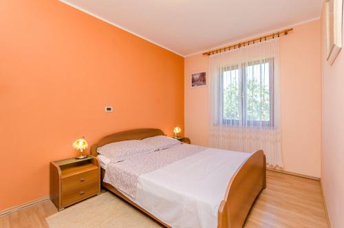 una camera da letto con pareti arancioni, un letto e una finestra di Apartments Marija a Umag (Umago)