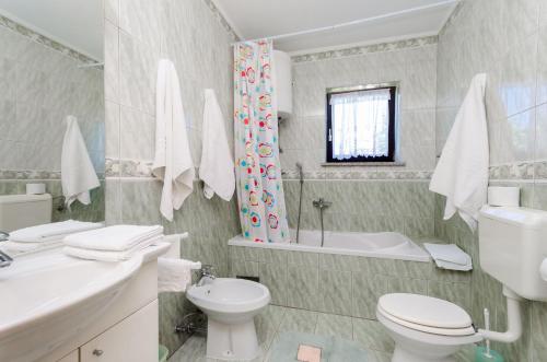 a bathroom with a toilet and a sink and a tub at Apartments Marija in Umag