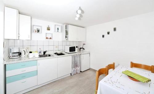 a kitchen with white cabinets and a table with a tablecloth at Apartment Sanja in Martina