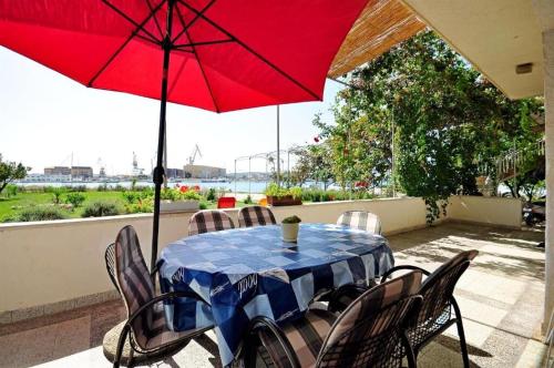 - une table et des chaises avec un parasol rouge sur la terrasse dans l'établissement House Ivica, à Trogir