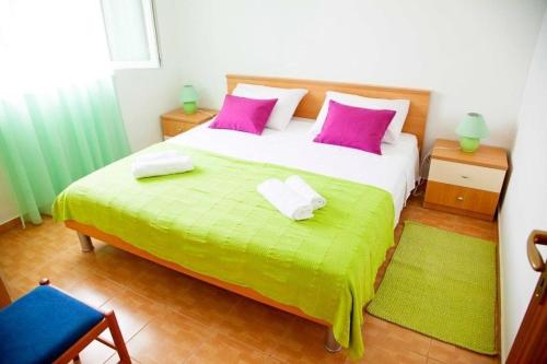 a bedroom with a large bed with pink and green sheets at Apartment Marija in Donje Selo na Šolti