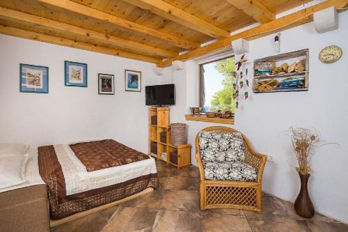 Un dormitorio con una cama, una silla y un televisor en House Vesna Kupinova, en Milna
