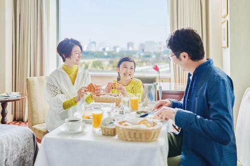 a group of people sitting around a table eating food at Imperial Hotel Tokyo in Tokyo