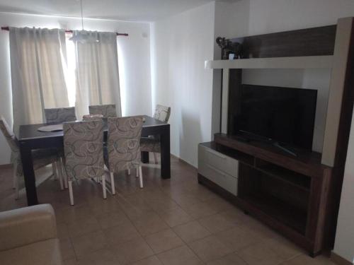 Sala de estar con mesa de comedor y TV en Olivia Apart frente plaza centro con cochera en Villa María