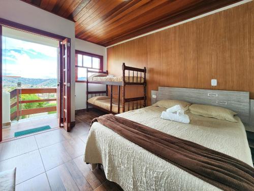 a bedroom with a large bed and a balcony at Pousada Araucária Village in Campos do Jordão