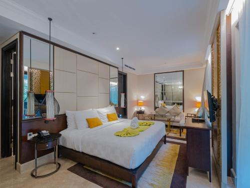 a bedroom with a large bed and a living room at Jambuluwuk Oceano Seminyak Hotel in Seminyak
