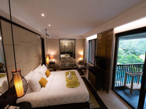 a bedroom with a large bed and a balcony at Jambuluwuk Oceano Seminyak Hotel in Seminyak